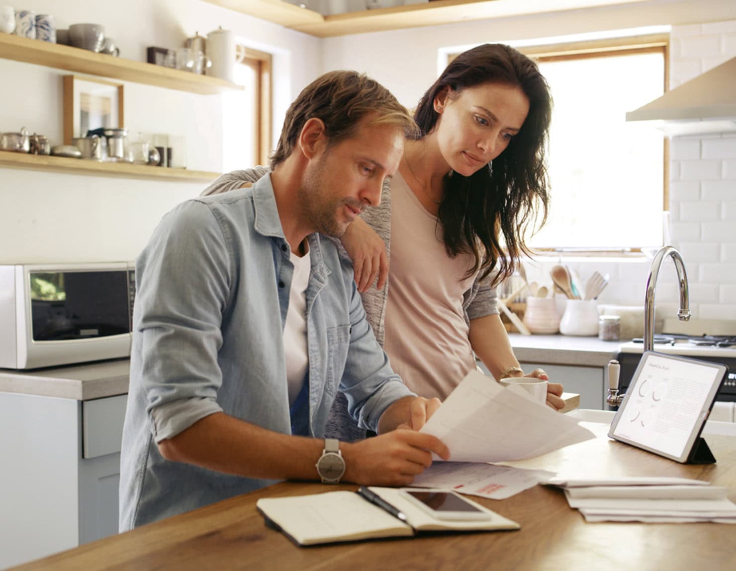 Couple reviewing finances and documents at home representing homeowner resources for budgeting and property planning